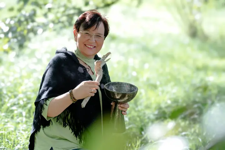 Nicole Dreis lacht, Feder und Räucherkelch in den Händen