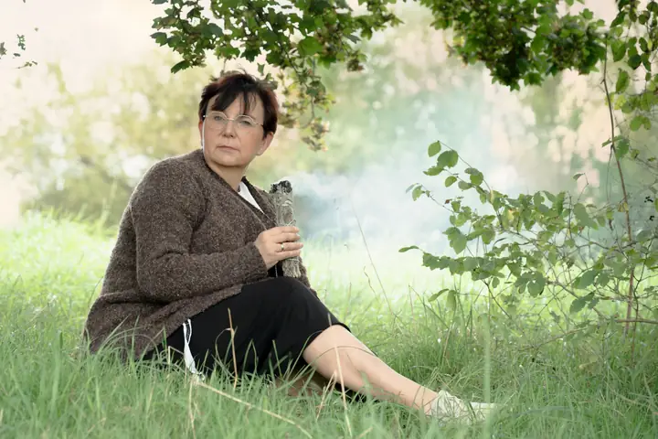 Nicole Dreis mit Räucherbündel unter einem Baum
