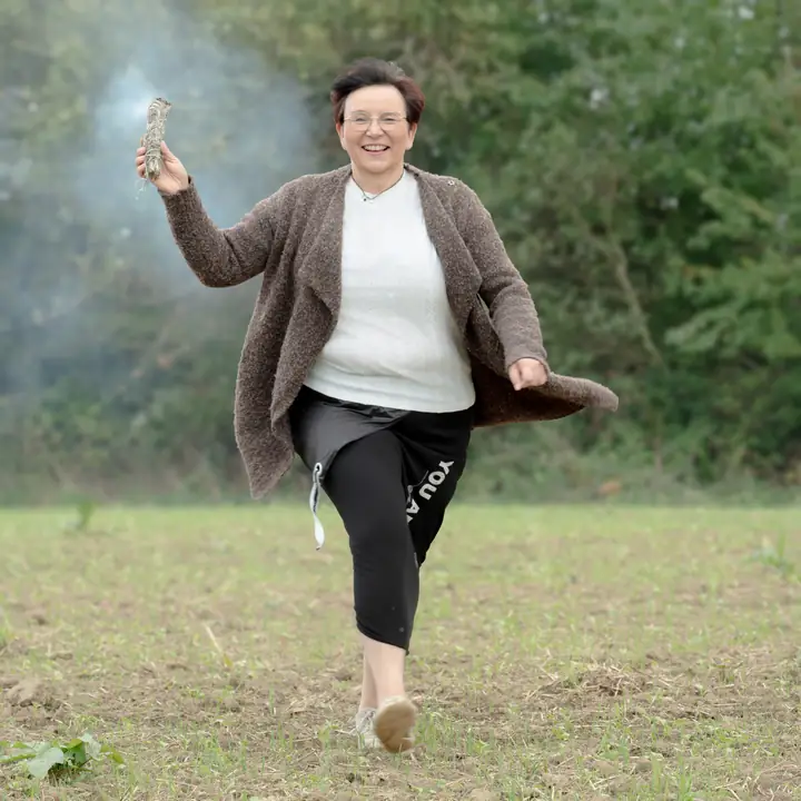 Nicole Dreis läuft lachend mit einem Räucherbündel über das Feld