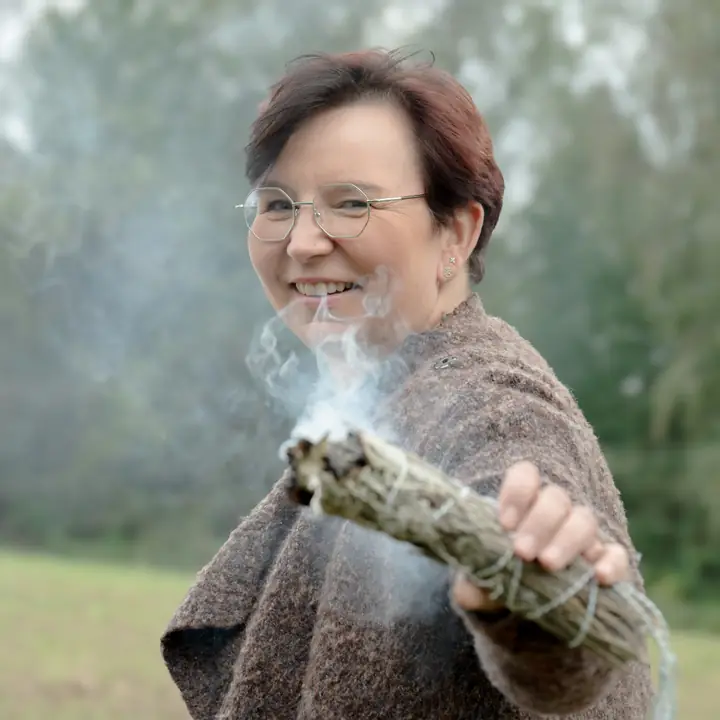 Nicole Dreis lacht hinter einem rauchenden Räucherbündel