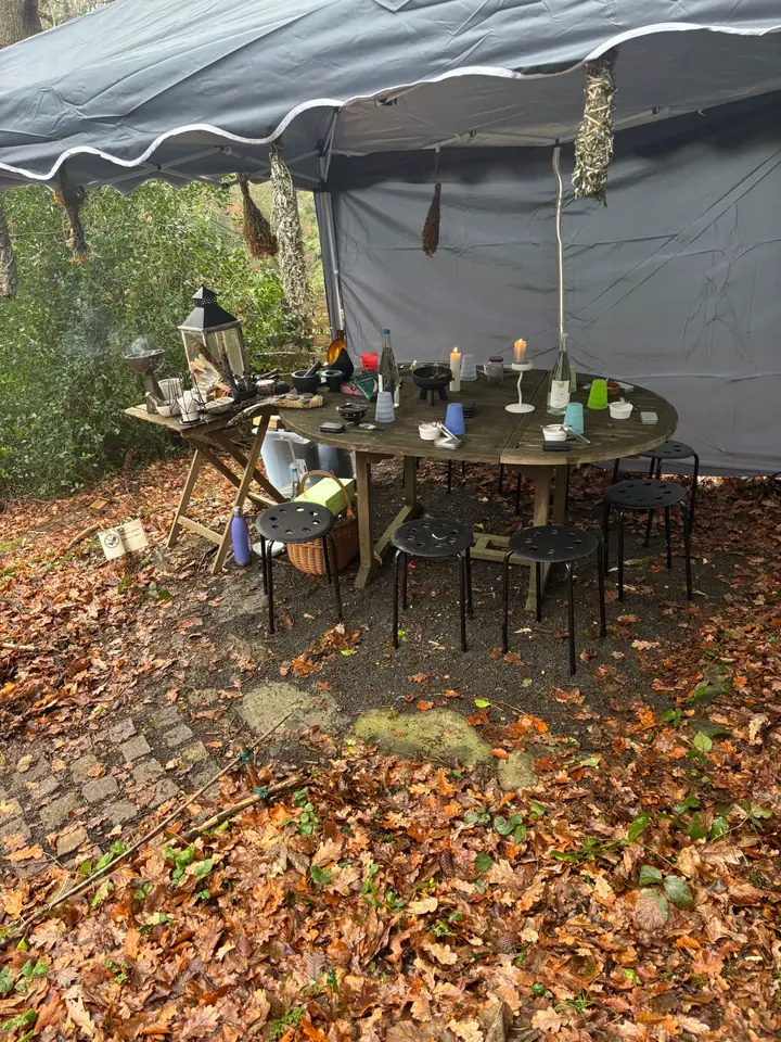 Ritualplatz unter einem Zeltdach im Herbstlaub, gedeckter Tisch mit Kerzen